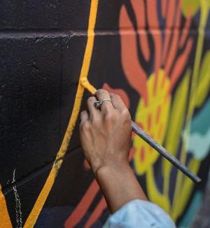 A hand holding a paintbrush, painting a wall 